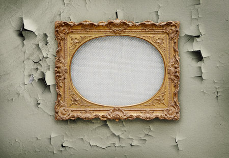 Empty canvass in old golden round frame on a grunge wallの写真素材