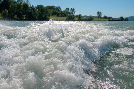 White motorboat tracks on the waves with a blurred green hills on the horizonの写真素材