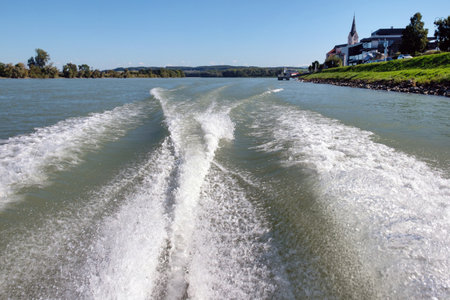 White motorboat tracks on the waves with a blurred village background on the horizonの写真素材