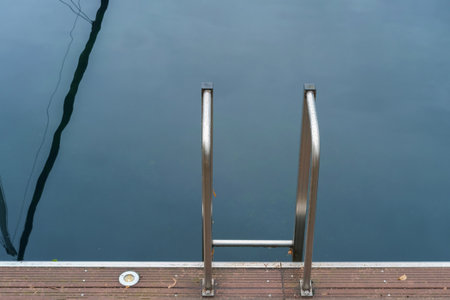 Metal handrail for descent into the lake, pier on the lake and calm lake water on backgroundの写真素材