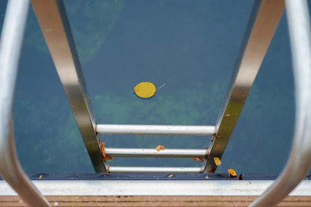 Metal handrail for descent into the lake, calm lake water on background, selective focus