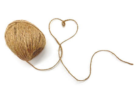 An unwound ball of thread, the thread forms a heart on a white background. Jute for gifts, souvenirs...
