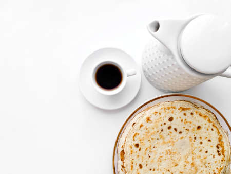 Pancakes with tea or coffee with a kettle on a white isolated background with a copy location....