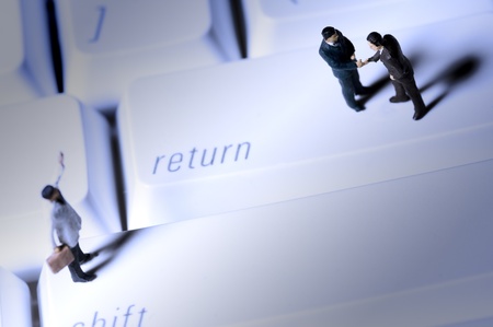 Three business man figures on keyboardの写真素材