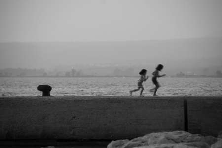 Two children running across the pierの写真素材