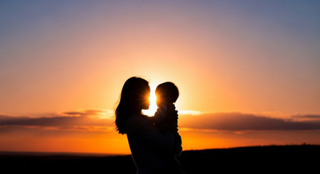 Silhouette of a mother and her little son on the sunset backgroundの素材
