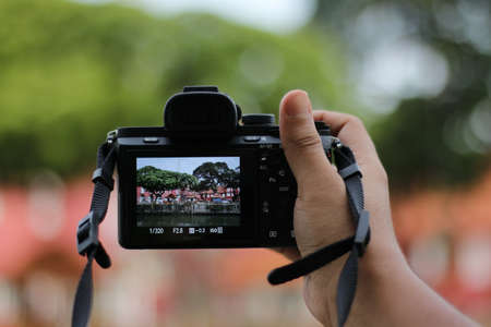 Hands holding a digital camera in front of a blurred background.の写真素材