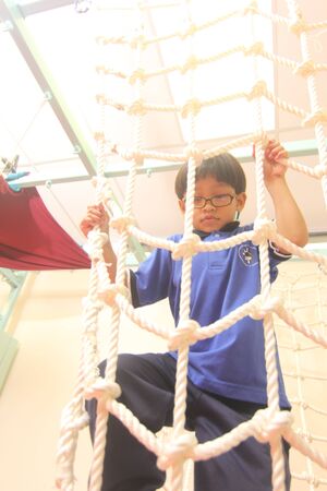 Nerd child climbing on the rope の素材