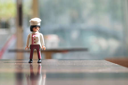 Miniature cook girl with uniform waiting for supplies and looks sideways. Playmobil toys.のeditorial素材