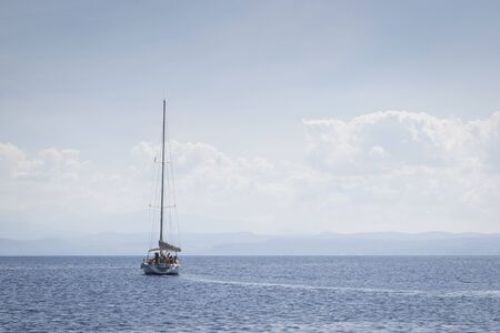 A sailing boat travels in the endless blue of the Aegean beautiful Sea in summer.の写真素材