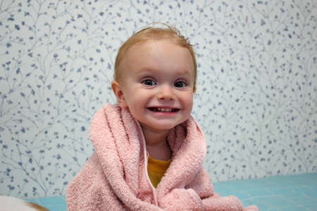A little girl is wrapped in a towel after bathing. close-up portrait.の写真素材