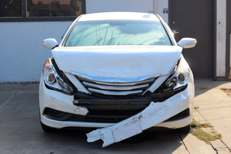 Broken white car after an accident. The headlights, hood, radiator, bumper, and fenders were broken. Photo close-up.の写真素材