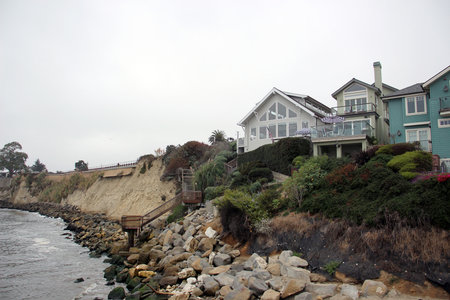 Rocky coastline with houses on the Pacific Ocean shore in foggy weather in Capitola Californiaの写真素材