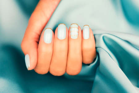Beautiful female fingers with blue manicure and sparkles. Colored French manicure with sparkles.の写真素材