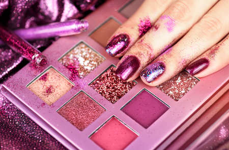 Festive purple manicure with sparkles and shimmer. Beautiful female hand with shiny purple manicure on a purple background. Christmas manicure.の写真素材