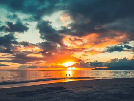 Multi color bright sunset over sea sand beach. People relax and watch sun down landscape. Blue and orange clouds sky. Wonderful nature landscape during sunset. Travel, tourism, adventure concept imageの写真素材