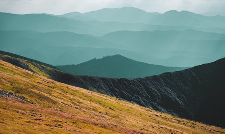 Panoramic landscape of mountain range in autumn morning. Orange grass hill slope, blue highlands silhouette, mountain peak top. Travel, hiking, freedom, active lifestyle. Carpathian mountains, Ukraineの写真素材