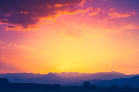 Beautiful mountain range with sunset sun in orange sky with colorful clouds. Amazing nature scenery. Natural texture and backgroundの写真素材