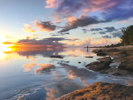 Bright tropial sunset reflected in ocean water. Colorful clouds in sky and rocky seashore. Amazing natural summer scenery. Wonderful Nature landscape during sunset. Travel, tourism, relax.の写真素材