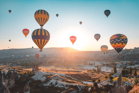 Cappadocia sunrise hot air balloons fly over Goreme valley landscape with stone caves. People in colorful hotair ballons enjoy wonderful dawn watching, aerial view. Tourism, travel holidays backgroundの写真素材