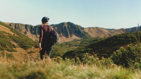 Tourist woman hike trekking trail in autumn mountains. Girl with backpack walking highland meadow in...