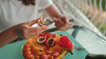 Woman eating passion fruit close up. Exotic tropical fruits plate. People lifestyle travel on summer holiday vacationの写真素材