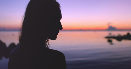 Woman silhouette against colorful sunset sky reflected in sea water. Bright blue pink and orange colors. Stunning natural background. Travel, tourism, holiday, relax.の写真素材