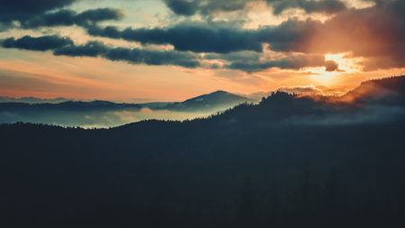 Epic foggy colorful sunrise in alp mountains. Dramatic clouds flow in bright sky, sun glow rising over mountain peak with golden light beams. Beautiful nature summer landscape.の写真素材