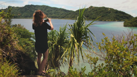 Woman enjoy tropical French Polynesia landscape standing on cliff edge with palm trees. Female make...