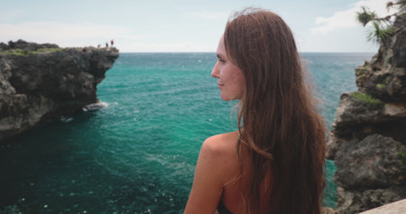 Romantic girl enjoy sea view with rock cliff and tourquies water. Long hair slim brunette young woman back view. Travel tourism, holiday, hiking, freedom. Indonesia, Wild Sumba Island, Weekurri Lagoonの写真素材
