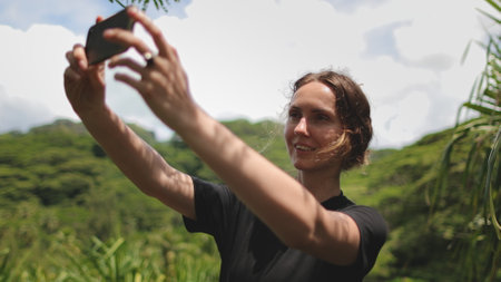 Woman in tropical rainforest jungles make selfie portrait on mobile phone. Green nature wild island landscape. Outdoor lifestyle travel on summer holiday vacation. Slowの写真素材