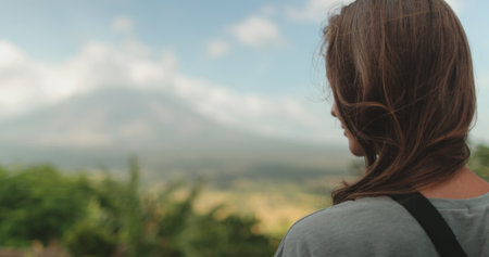 Woman stands near towering mountain, enjoy view on Legazpi Mountains Volcano, Philippines. Asia wild...