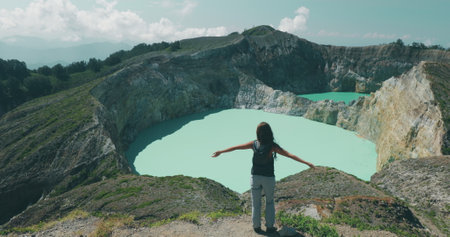 A woman standing on top of a mountain next to a beautiful lake in the Philippines, with a volcano and crater lakes in the background.の写真素材
