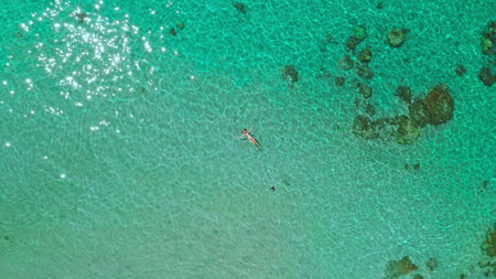 Floating peacefully in a turquoise lagoon. A woman enjoys a relaxing bath surrounded by vibrant...