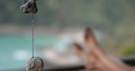 Relax and quiet outdoor concept. Shells and corals on threads swaying in the wind. Barefoot legs in...