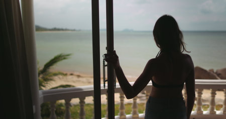 Woman silhouette walking window terrace balcony, looking out ocean landscape. Tropical nature...