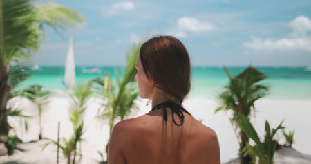 A woman stands on the sandy shore of Boracay Islands White Beach, gazing out at the vast ocean ahead of her.の写真素材