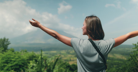 Young tourist is embracing the breathtaking view of mayon volcano in the philippines, feeling a sense of freedom and aweの写真素材