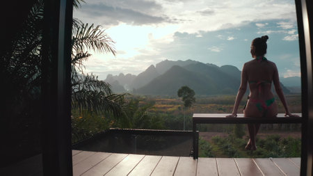 Tourist is enjoying a relaxing moment on a terrace, taking in the breathtaking view of lush green mountains in thailandの写真素材