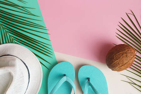 Palm leaves, summer hat, flip-flops and coconut on a pink, green and beige texture with copy space. Summer vacation or trip. Top view, flat layの写真素材