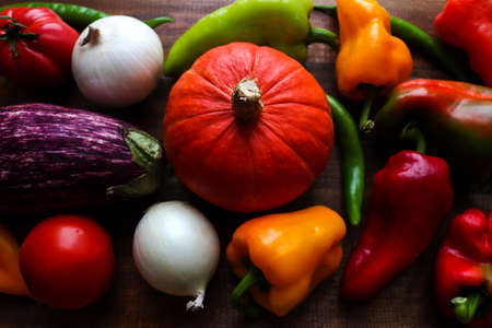 Colorful vegetables background. Harvest. Fresh raw sweet peppers, tomatoes and garlic on wooden...