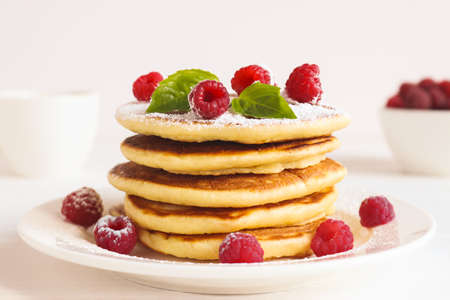Traditional American breakfast. Delicious pancakes with raspberries, basil, and powdered sugar. Close-up, selective focusの写真素材