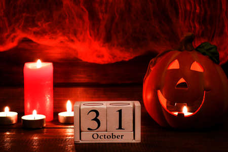 Halloween card with copy space for congratulation. Calendar dated October 31, Jack-o-latern and candles against the background of a cobweb. Selective focusの写真素材