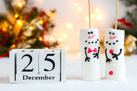 Cute Christmas or New Year greeting card with marshmallow snowmen and calendar dated December 25...