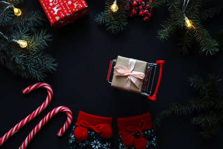 Christmas card with Christmas tree branches, Christmas socks, gifts and wooden letters MERRY CHRISTMAS on a black background. Festive and holiday background. Top view, flat lay.の写真素材