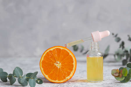 Bottle of cosmetic skincare serum with dropper, orange and eucalyptus. Beauty concept. Citrus...