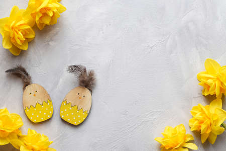 Composition with yellow daffodils and wooden chicken toys against grey textured background with copy space. Holiday symbols. Top viewの写真素材