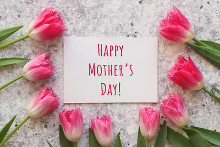 Mothers Day greeting card. Beautiful pink tulips, and paper with text Happy Mothers Day. Top view,...