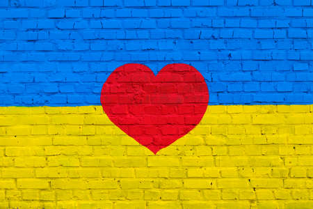 Brick wall is painted in the colors of the Ukrainian national flag - yellow and blue and red heart in the middle. textured background. Symbol of love for Ukraine.の写真素材