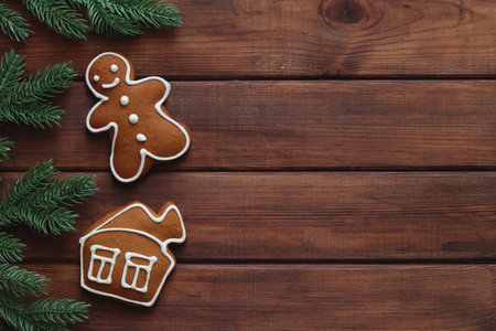 Christmas festive background with copy space. Gingerbread man and house cookies with Christmas tree branches on the wooden table. Top view, flat layの写真素材